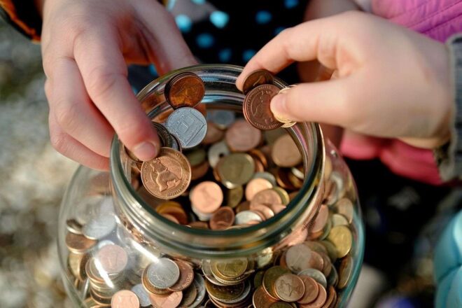 Mains plaçant des pièces dans un bocal d épargne traditionnel
